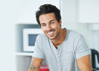 Hes happy in his bachelor flat. Cropped portrait of a handsome young man in his kitchen.