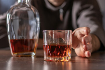 Alcoholism, alcohol addiction and people concept - male alcoholic pulls his hand to a glass of alcohol