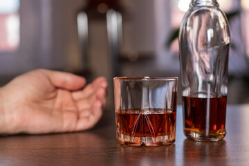 Alcoholism, glass whiskey and man hand lyins on table . Treatment of alcohol addiction, suffer abuse problem alcoholism concept