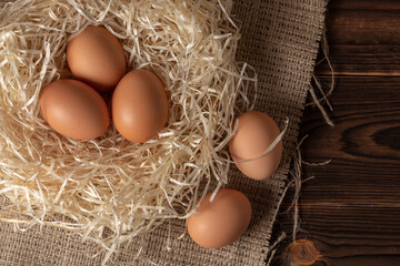 Hay with eggs on wooden background.