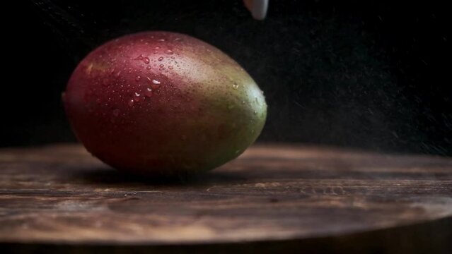 ripe and very juicy mango. royal fruit. close-up. Slow motion. dark background. mango closeup. red mango peel covered with fresh water drops