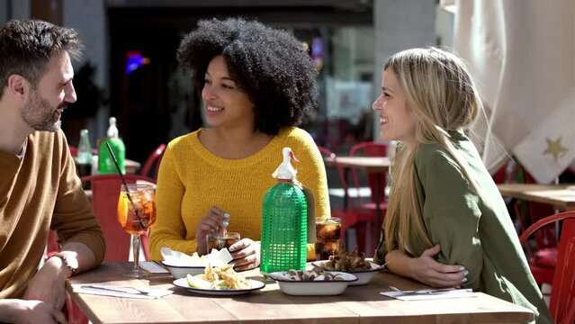Video of happy group of friends talking and having fun while having drink at terrace restaurant.