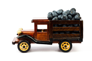 Ripe blueberry in wooden toy truck on white background.