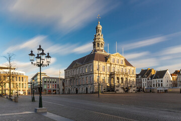 Maastricht, Netherlands 02-21-2022 Long exposure image creating moving clouds with a view on the Skyline of Maastricht and the town hall at the central Market square and the statue of Minckeleers