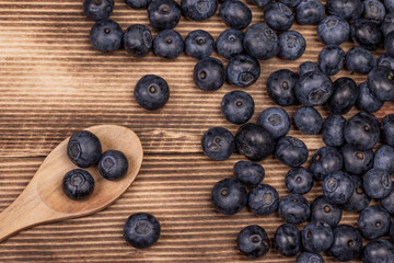 Blueberry background. Ripe blueberry with wooden spoon on wooden background.