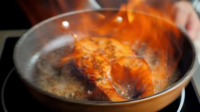 excellent grilled fish steak. French cuisine. the chef pours aged rum into a hot frying pan with a nice piece of meat. fire blazes in a frying pan. masterly roasting, delicious fish saik. alcohol evap