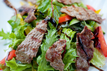 Salad with fried meat and fresh vegetables. A dish from a chef in a restaurant.