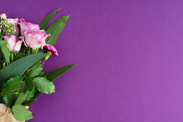 Bouquet with purple roses and eucalyptus on purple background. Copy space. Top view.