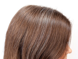 A woman's head with a parting of gray hair that has grown roots due to quarantine. Brown hair on a woman's head close-up. Hair regrowth 