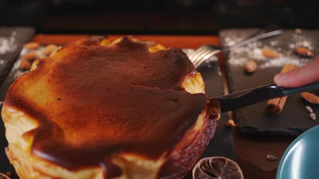 hand slicing crusty classic basque san sebastian cheesecake with cream cheese