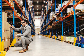 A warehouse inspector with bar and qr code scanner in hands checking on orders in boxes.