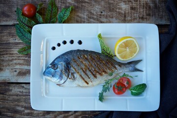 Grilled or fried fish. Decoration of vegetables and lemon. The concept of a menu for a restaurant or cafe.