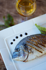 Grilled or fried fish with white wine. Decoration of vegetables and lemon. The concept of a menu for a restaurant or cafe.