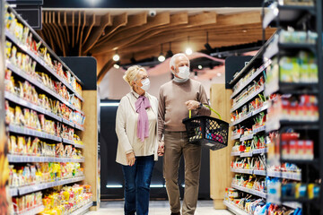 Happy senior couple purchasing groceries at supermarket during covid 19.