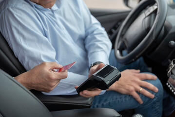 unrecognizable cab driver holding a bank payment terminal to process credit card payment purchases - transport concept, cab, taxi and technology