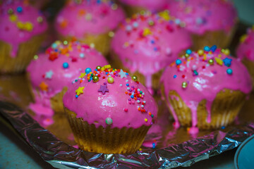 Freshly baked vanilla muffins are garnished with sweet icing and topping.