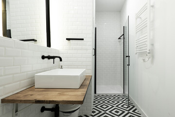 Modern cloakroom with a black and white tiled floor, a white porcelain sink, white tiles, black...