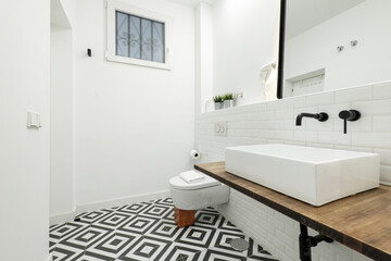 Modern toilet with black and white hydraulic floor with white porcelain sink, white tiles and black...