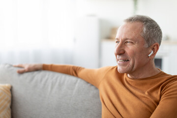 Calm mature man having rest at home listening to music