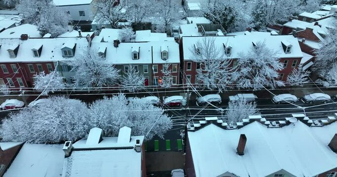 Truck shot of colorful row homes in fresh winter snow in USA. Flurries in evening. Light on. Establishing shot.
