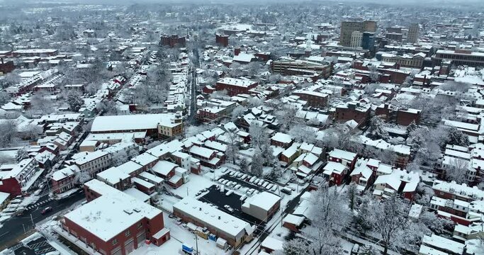 American city covered in fresh winter snow. Evening establishing shot of large town in USA. Snowy scene.