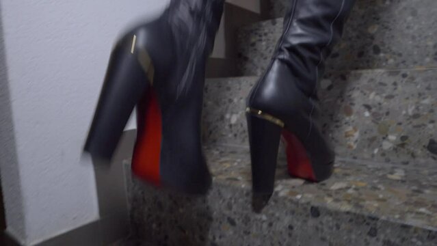 woman walks up the stairs in her home in black sexy high-heeled platform boots