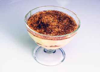 Traditional Italian home made tiramisu dessert in a glass cup on plane white background
