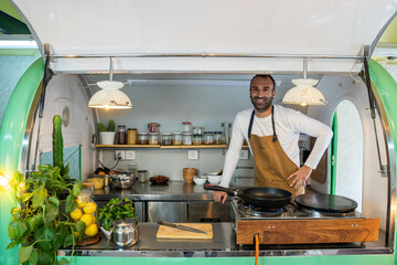 Cook smiling at the camera in his food truck. Happy with his small business and his job. 