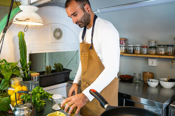 General flat cook pouring oil in his small vegetarian food truck business. 