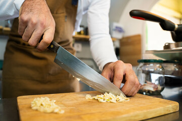 Unrecognizable cook chopping garlic for his recipe. 