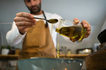 Chef pouring oil to prepare his dish. 