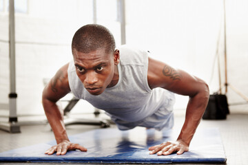 Fototapeta premium Only 10 to go. Seriously focused man doing push ups in a gym.