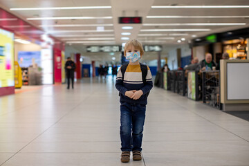 Obraz premium Cute baby boy waiting boarding to flight in airport transit hall near departure gate. Active family lifestyle travel by air with children