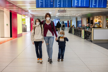Mother with two children, waiting boarding to flight in airport transit hall near departure gate. Active family lifestyle travel by air with children