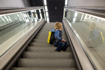 Cute  baby boy waiting boarding to flight in airport transit hall near departure gate. Active family lifestyle travel by air with children