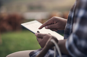 The modern way to manage a farm. Shot of an unrecognisable man using a digital tablet while working on a cow farm.