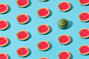 Arranged half watermelon and one whole on a blue pastel background. Minimal pattern and design.