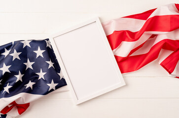 Fototapeta premium Blank white photo frame for mockup design on American national flag wooden background