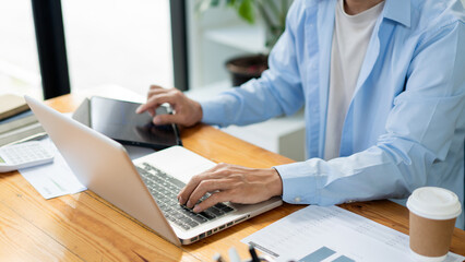 Business analyst concept the businessman using both computer laptop and tablet to monitor the sale of stock