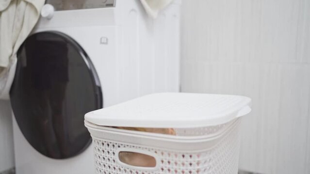 funny little girl blonde playing hide and seek in bathroom in laundry basket.