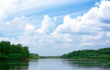 Blue sky on a calm summer day. Bend of the river in Siberia, forest near water