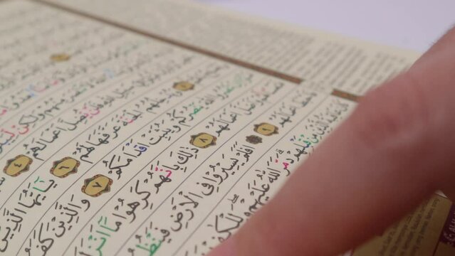extreme close up hands pointing on some verses of an koran