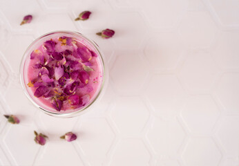 Pink rose milk with rose petals in a glass. Healthy drink moon milk. Top view. Copy space.