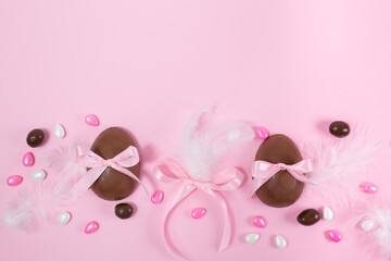 Colorful Easter chocolate eggs, flat lay on pink background. Happy Easter. Stylish Easter layout. Greeting card or banner template