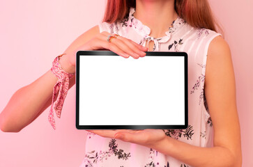 Young woman holding tablet with blank screen on pastel pink background. Free copy (text) space.