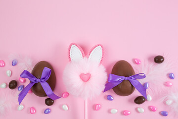Colorful Easter chocolate eggs, flat lay on pink background. Happy Easter. Stylish Easter layout. Greeting card or banner template