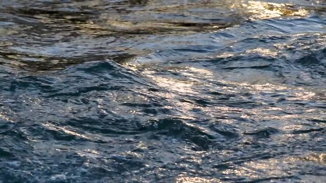 Running water at river with sun flickering on surface