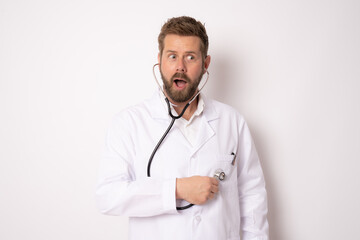 Laughing funny young bearded doctor man wearing white medical gown standing hold stethoscope isolated on white background. Medicine concept.