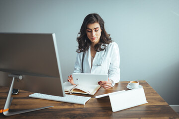 Confident female doctor sitting at office desk, health care and prevention concept. Portrait of friendly physician woman. Medicine concept. Portrait Of Smiling Female Doctor