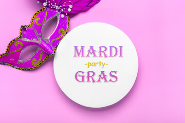 Mardi gras lettering. Congratulation card with mask on white podium on violet background Top view...